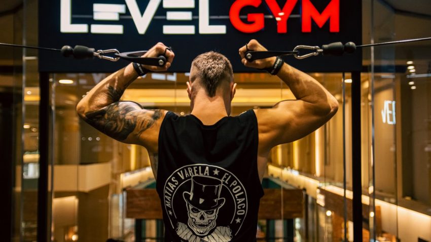 Back view of a muscular man working out in a modern gym, focusing on strength and fitness.